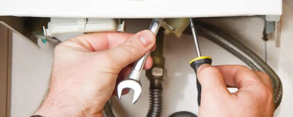 Boiler repair technician tightening pipe fittings and connections in Denver, CO