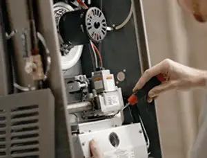 Furnace repair technician inspecting internal components and wiring in Denver, CO