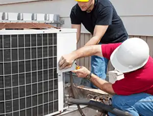 HVAC technicians repairing an outdoor AC unit on a rooftop in Denver, CO