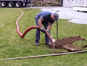 Septic pumping technician servicing a residential septic tank with a vacuum hose in Denver, CO