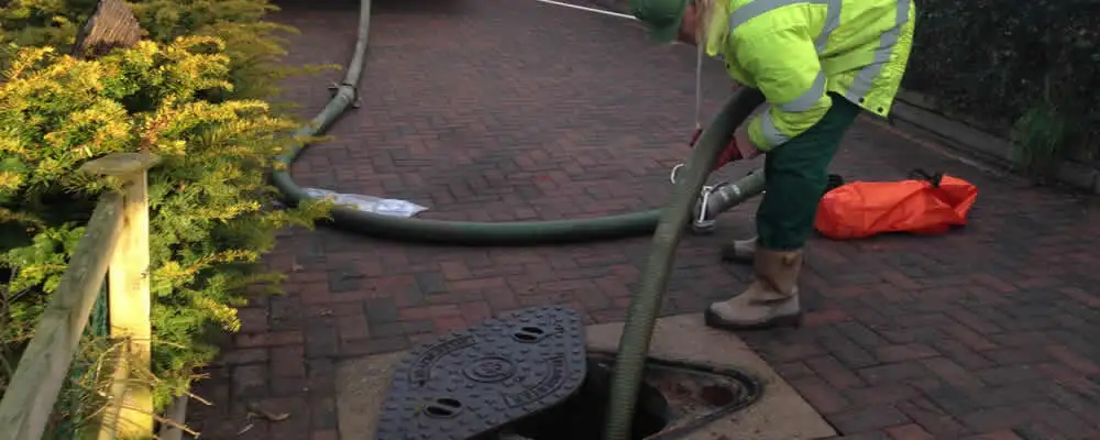Septic tank cleaning technician servicing a septic tank with a vacuum hose in Denver, CO