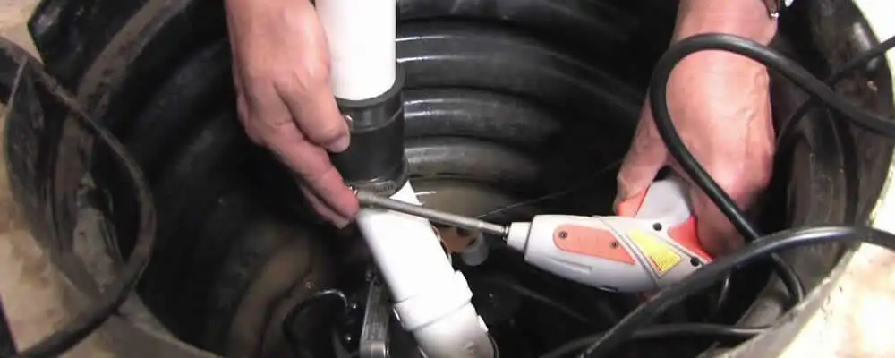 Sump pump installation technician connecting PVC discharge piping in Denver, CO