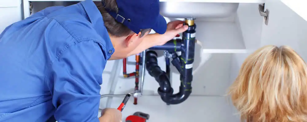 Plumber repairing under-sink drain pipes and fittings in Denver, CO